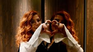 Femme qui fait un ceur avec un miroir pour symboliser l'Amour de soi: comment trouver l'Amour