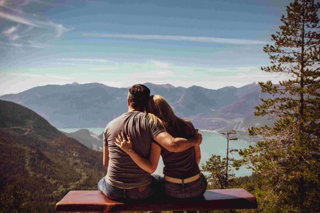 trouver le Grand Amour: couple de dos et assis sur un banc qui contemple un lac en montagnes depuis un sommet
