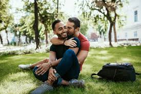 trouver le Grand Amour: couple d'hommes enlassé et assis dans un parc riant. 