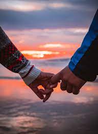 trouver le Grand Amour: mains se tenant par le petit doigt dans un coucher de soleil sur la mer